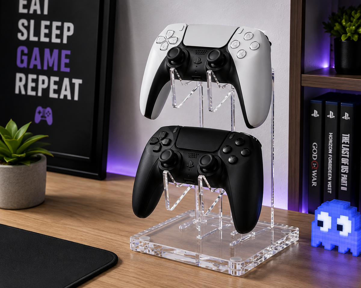 2-tier acrylic controller stand with white and black PS5 controllers on dark gaming desk with RGB lighting and keyboard