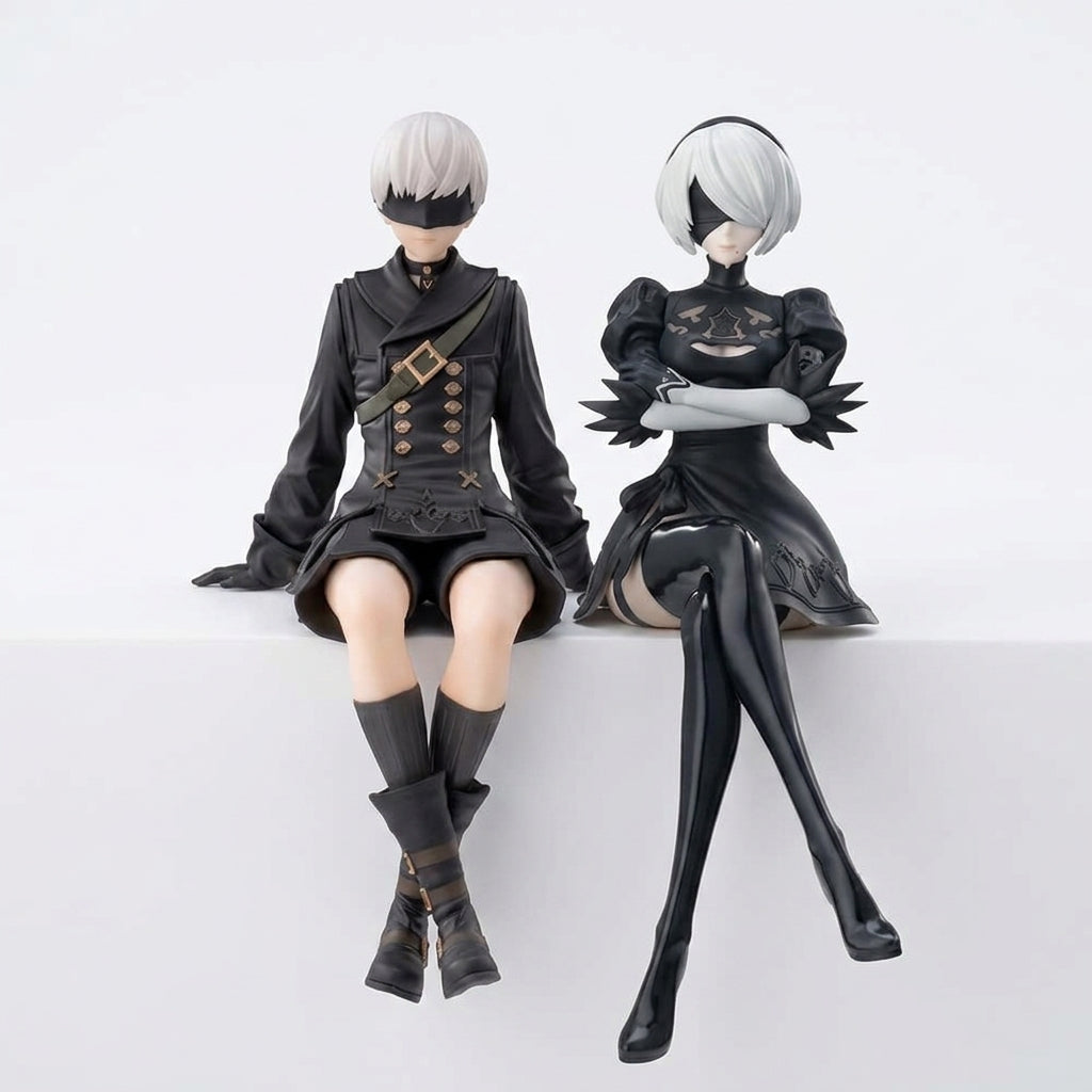 2B and 9S inspired PVC collectible figures seated side by side in black YoRHa uniforms on white background showing full set of both characters